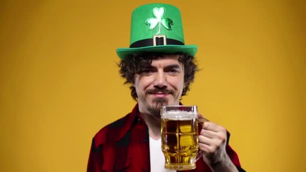 Día de San Patricio. Joven hombre Oktoberfest sirviendo jarra de cerveza grande con bebida aislada sobre fondo amarillo . — Vídeos de Stock