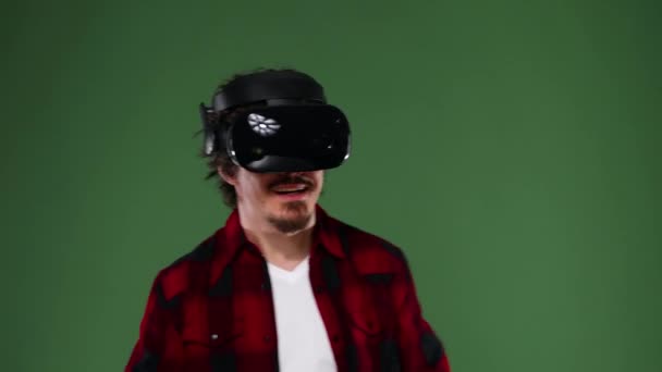 Joven con el pelo rizado usando un casco VR y experimentando realidad virtual aislado sobre fondo verde. Clave de croma . — Vídeos de Stock