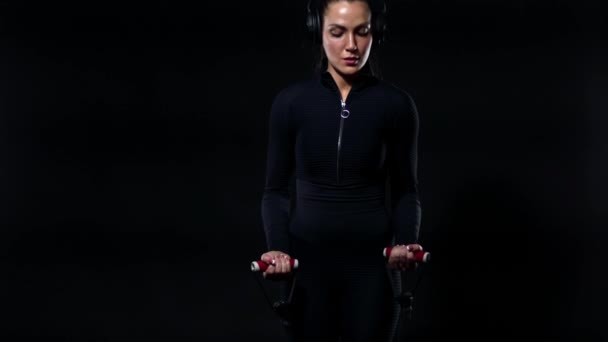 Spor ve spor konsepti. Spor giyim ve kulaklıklarda halterle çalışan formda bir bayan sporcu. Siyah arkaplanda izole edilmiş kız. — Stok video