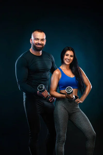 Giovane atleta di sport fitness muscolare in indumento di compressione. Allenamento in palestra con allenatore. Allenatore di uomini con reparto donne. Ragazza con i manubri . — Foto Stock