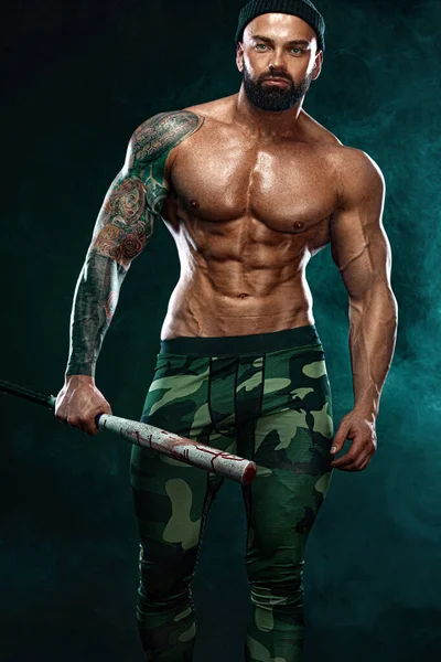 Kräftiger und fitter Mann Bodybuilder mit Baseballschläger zeigt Bauchmuskeln unter einem T-Shirt. sportlich muskulöser Kerl Athlet. Sport- und Fitnesskonzept. Herrenmode. — Stockfoto