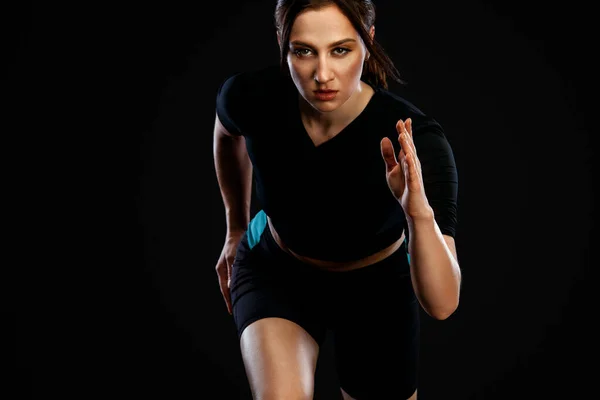 Sprinter and runner. Woman running on the black background. The concept of a healthy lifestyle and sport. Woman in sportswear. — Stock Photo, Image