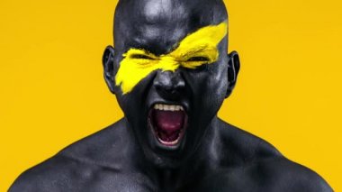 Erkek spor taraftarı takım zaferini kutluyor. Yüz sanatında sarı renkli ve siyah vücut boyalı vücut geliştirme sporcusu. Bodyart 'lı adamın renkli portresi.