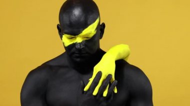 Vücudunda kadın eli olan bir adam. Sarı yüzlü ve siyah vücut boyalı vücut geliştirme sporcusu. Bodyart 'lı adamın renkli portresi.