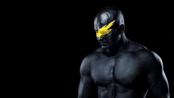 Άνθρωπος φίλαθλος και bodybuilder αθλητής με κίτρινο χρώμα στην τέχνη πρόσωπο και μαύρο χρώμα του σώματος. Πολύχρωμο πορτραίτο του τύπου με το αμάξωμα. Ο τύπος με τους αντίχειρες πάνω πινακίδα με δάχτυλα. — Αρχείο Βίντεο