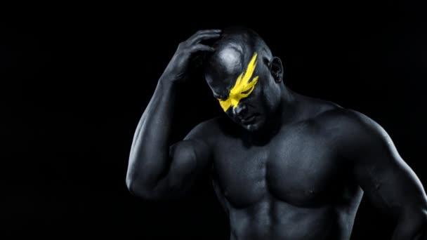 O homem tem uma boa ideia. Atleta fisiculturista com arte facial amarela e pintura corporal preta. Retrato colorido do cara com bodyart . — Vídeo de Stock