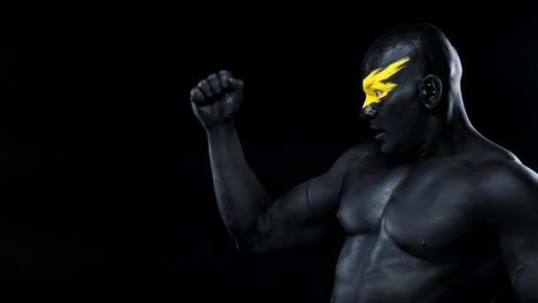 L'uomo sceglie lo spazio per copiare. Atleta culturista con viso giallo e vernice nera. Ritratto colorato del ragazzo con bodyart . — Video Stock