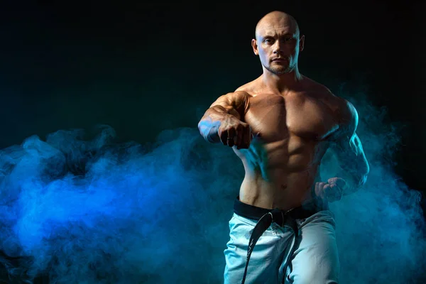 Καράτε ή taekwondo μαχητής σε μαύρο φόντο με καπνό. Fit άνθρωπος αθλητές bodybuilder σωματική διάπλαση και αθλητής. Κίνητρο αθλητισμού Mens. — Φωτογραφία Αρχείου