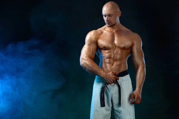 Karate oder Taekwondo Kämpfer auf schwarzem Hintergrund mit Rauch. Fit Mann Sportler Bodybuilder Körperbau und Athlet. Sportliche Motivation für Männer. — Stockfoto