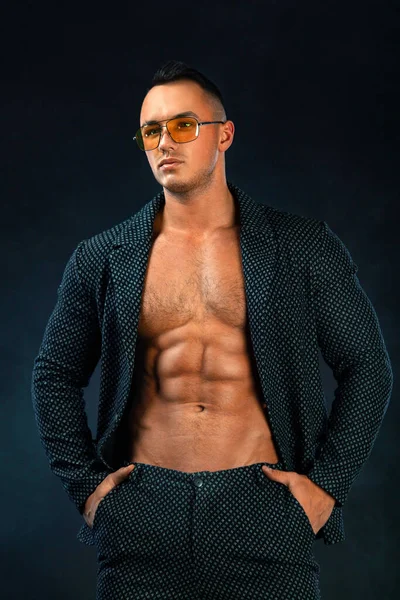 Portrait of handsome stylish man bodybuilder with naked torso in elegant suit. Guy in yellow sunglasses. — Stock Photo, Image