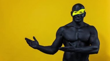 Adam kopyalama alanını seçiyor. Sarı yüzlü ve siyah vücut boyalı vücut geliştirme sporcusu. Bodyart 'lı adamın renkli portresi. Yavaş çekim.
