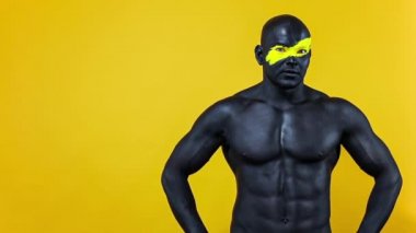Erkek spor hayranı ve vücut geliştirme sporcusu. Yüz ve vücut boyalarında sarı renkli. Bodyart 'lı adamın renkli portresi. Tamam işaretini parmaklarıyla gösteren bir adam. Yavaş çekim.