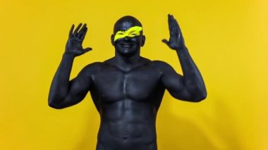 Erkek spor taraftarı takım zaferini ya da golünü kutluyor. Yüz sanatında sarı renkli ve siyah vücut boyalı vücut geliştirme sporcusu. Bodyart 'lı adamın renkli portresi. Yavaş çekim.