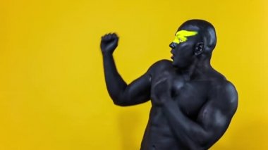 Adam kopyalama alanını seçiyor. Sarı yüzlü ve siyah vücut boyalı vücut geliştirme sporcusu. Bodyart 'lı adamın renkli portresi. Yavaş çekim.