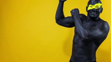 Adam kopyalama alanını seçiyor. Sarı yüzlü ve siyah vücut boyalı vücut geliştirme sporcusu. Bodyart 'lı adamın renkli portresi. Yavaş çekim.