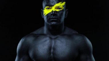 Yüz resmi ve siyah vücut boyası üzerinde sarı renk olan vücut geliştirme sporcusu portresi. Bodyart 'lı adamın renkli bir fotoğrafı. Yavaş çekim.