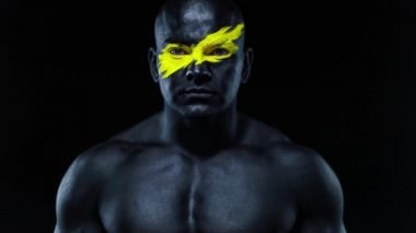 Yüz resmi ve siyah vücut boyası üzerinde sarı renk olan vücut geliştirme sporcusu portresi. Bodyart 'lı adamın renkli bir fotoğrafı. Yavaş çekim.