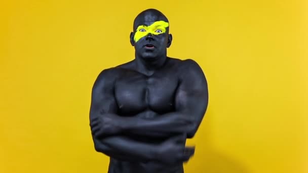Man sports fan celebrates team victory or goal. Bodybuilder athlete with yellow color on face art and black body paint. Colorful portrait of the guy with bodyart. Slow motion. — Stock Video