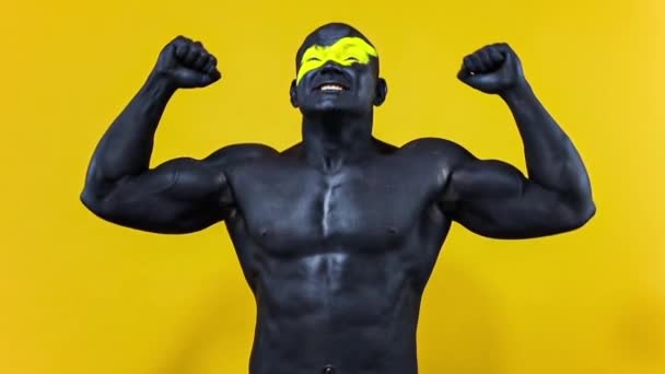 Gli appassionati di sport maschili celebrano la vittoria o l'obiettivo della squadra. Atleta culturista con colore giallo sulla faccia arte e vernice corpo nero. Ritratto colorato del ragazzo con bodyart. Rallentatore . — Video Stock