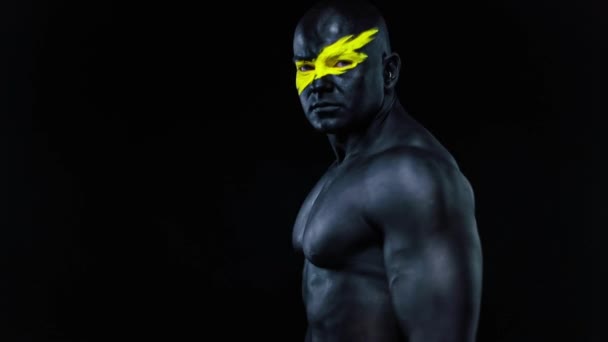 Man sportfan en bodybuilder atleet met gele kleur op gezicht kunst en zwarte body paint. Kleurrijk portret van de man met bodyart. Langzame beweging. — Stockvideo