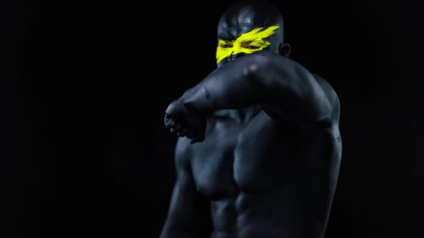 Männersportfan und Bodybuilder-Athlet mit gelber Farbe auf Gesicht und schwarzer Körperfarbe. Buntes Porträt des Typen mit Bodyart. Zeitlupe. — Stockvideo