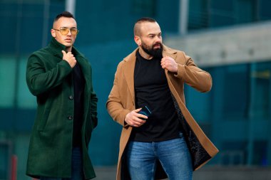 İş merkezinin yanındaki montlu genç iş adamı. Sonbahar ya da bahar erkek modası.