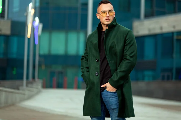Jovem homem de negócios de casaco verde no centro de negócios olhando para o futuro. Outono ou primavera homens moda olhar . — Fotografia de Stock