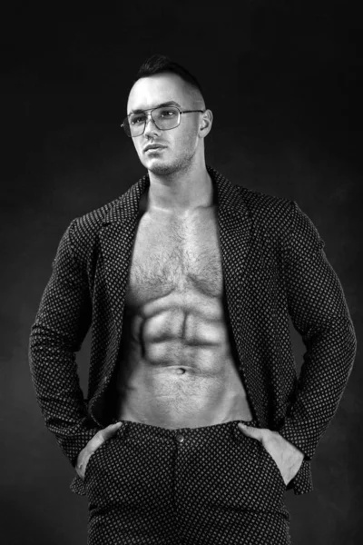 Portrait of handsome stylish man bodybuilder with naked torso in elegant suit. Guy in glasses. Black and white photo — Stock Photo, Image