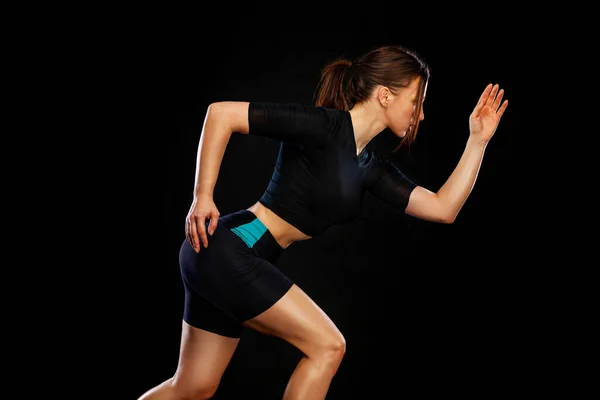 Menina velocista e corredora. Conceito de corrida. Uma mulher a correr sobre o fundo negro. O conceito de um estilo de vida saudável e esporte. Mulher de sportswear . — Fotografia de Stock