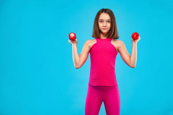 Ragazza che fa esercizi di fitness con manubri su sfondo blu — Foto Stock