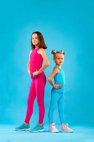 两个女孩在蓝色背景下进行健身锻炼后休息。儿童生活方式概念. — 图库照片