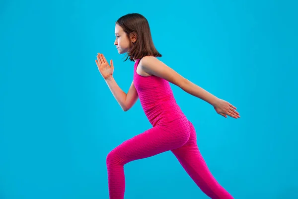 Дівчинка робить фізичні вправи на рожевому і рожевому тлі в спортивному одязі. Спортивна концепція . — стокове фото