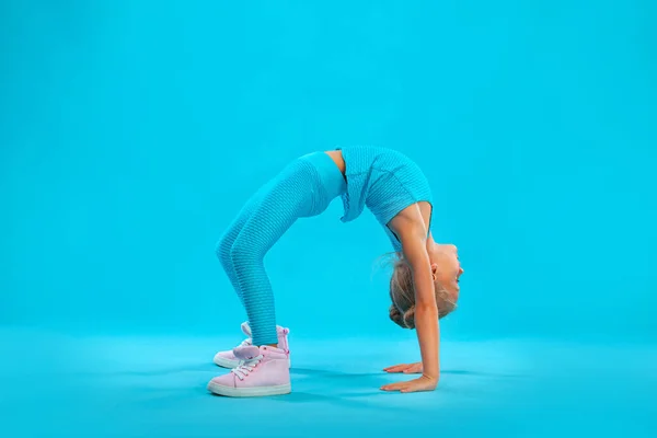 Niña haciendo ejercicios de fitness sobre fondo rosa y rosa en ropa deportiva. Concepto deportivo . — Foto de Stock