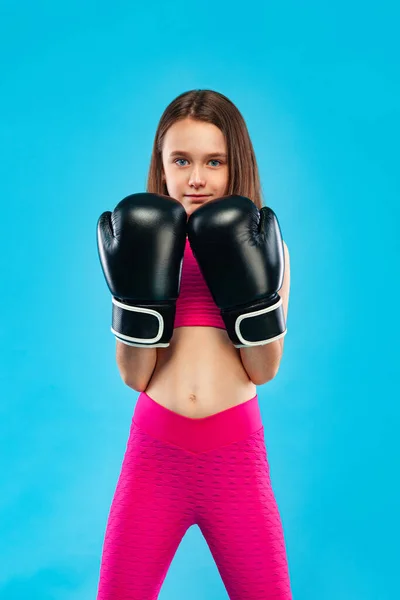 Concepto de boxeo y fitness. Deportista, niña boxeadora peleando con guantes sobre fondo azul . — Foto de Stock