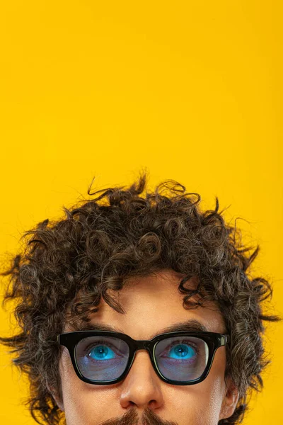Portrait of happy bearded man with curly hair pointing finger up at copyspace isolated over yellow background. Guy in blue sunglasses pick on great idea. — 图库照片