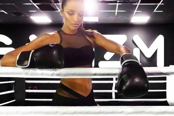 Женщина-боксер на ринге в спортзале. Юный спортсмен в боксёрских перчатках готовится к бою . — стоковое фото