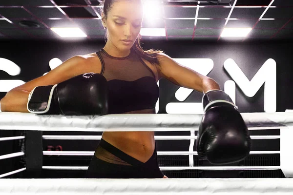 Mulher pugilista no ringue no ginásio. Jovem atleta em luvas de boxe se preparando para a luta . — Fotografia de Stock