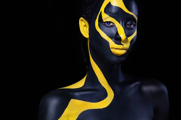 Femme avec de la peinture de corps noire. Joyeux jeune fille africaine avec art bodypaint. Un modèle étonnant avec un maquillage jaune. Gros plan sur le visage. — Photo