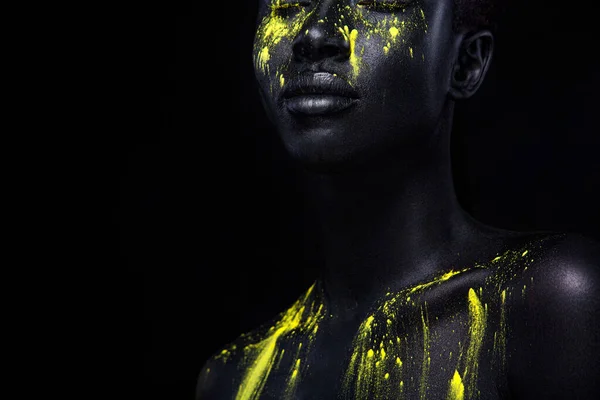 Kobieta z czarną farbą do ciała. Wesoła, młoda afrykańska dziewczyna z farbą do ciała. Niesamowity model z żółtym makijażem. Zbliżenie twarzy. — Zdjęcie stockowe