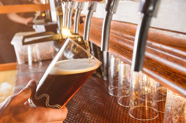 Barman ten dienste staat van bier uit de kraan — Stockfoto