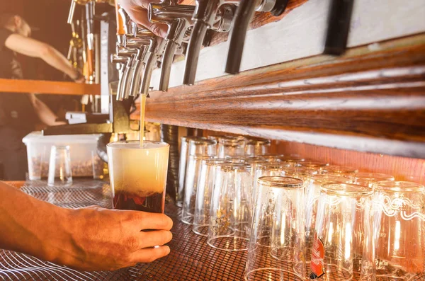 Barman is serving beer from faucet — Stock Photo, Image