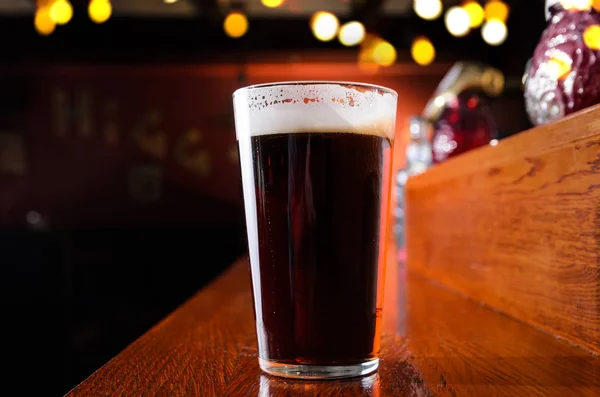 Glass of fresh beer on counter in pub — Stock Photo, Image