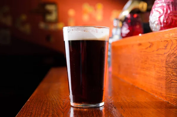 Glass of fresh beer on counter in pub — Stock Photo, Image