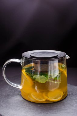 sıcak çay nane ve limon siyah arka plan üzerine bir cam tencerede ile