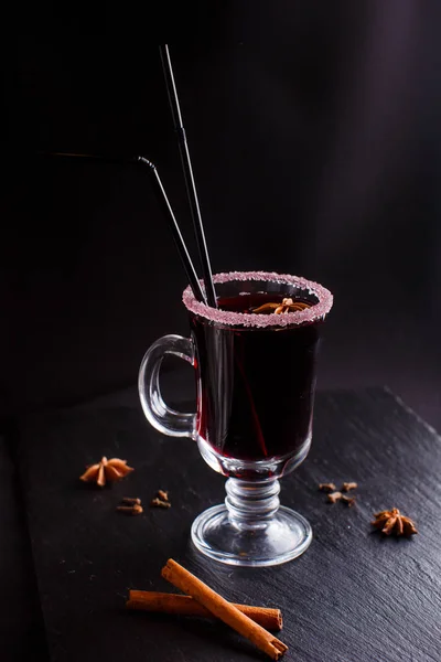 Mulled wine with cinnamon in the transparent glass on the black background — Stock Photo, Image
