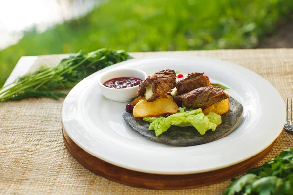 Kött med greener på en tårta bakgrund av naturen. Picknick — Stockfoto