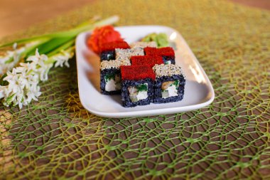 Geleneksel taze Japon suşisi siyah arka planda yuvarlanıyor.