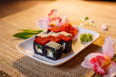 Geleneksel taze Japon suşisi siyah arka planda yuvarlanıyor.