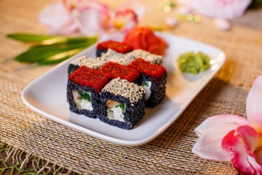 Geleneksel taze Japon suşisi siyah arka planda yuvarlanıyor.