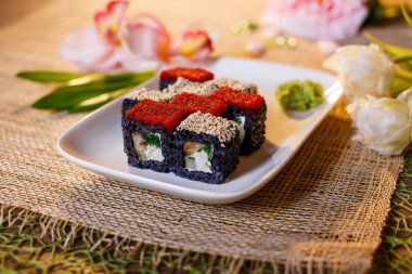 Geleneksel taze Japon suşisi siyah arka planda yuvarlanıyor.